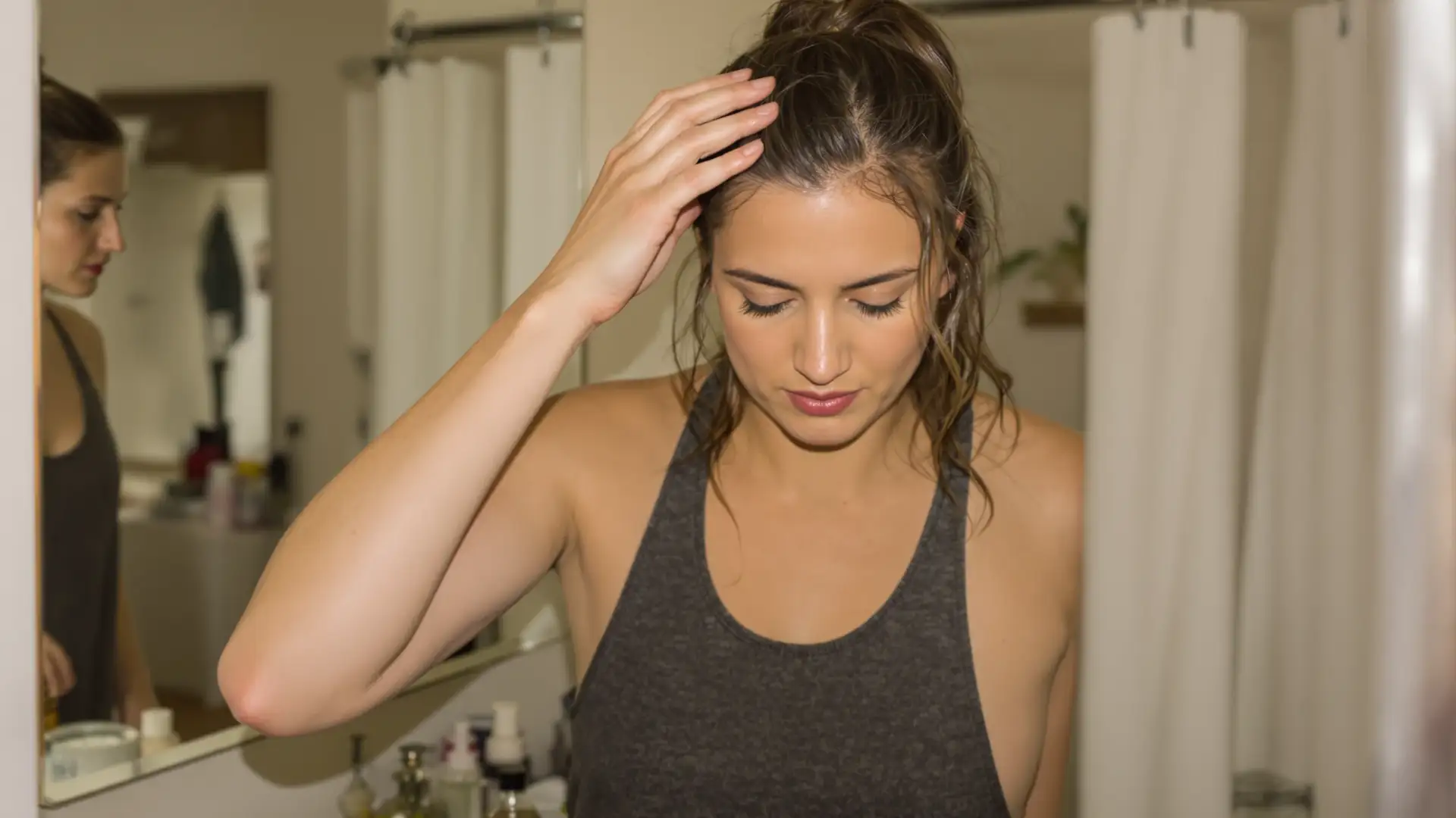Woman massaging castor oil into her scalp in a bathroom