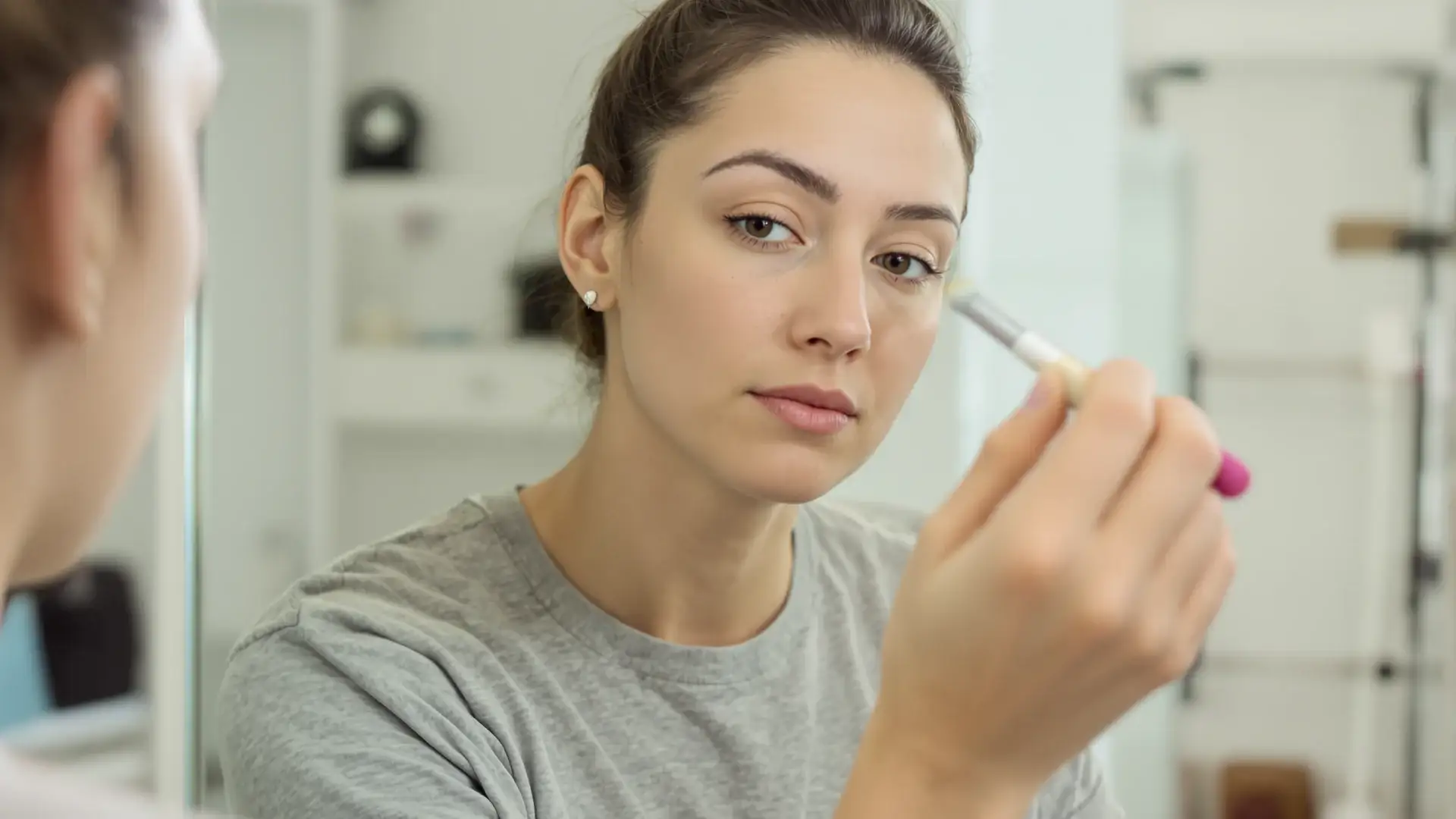 Applying minoxidil to an eyebrow with a small brush.