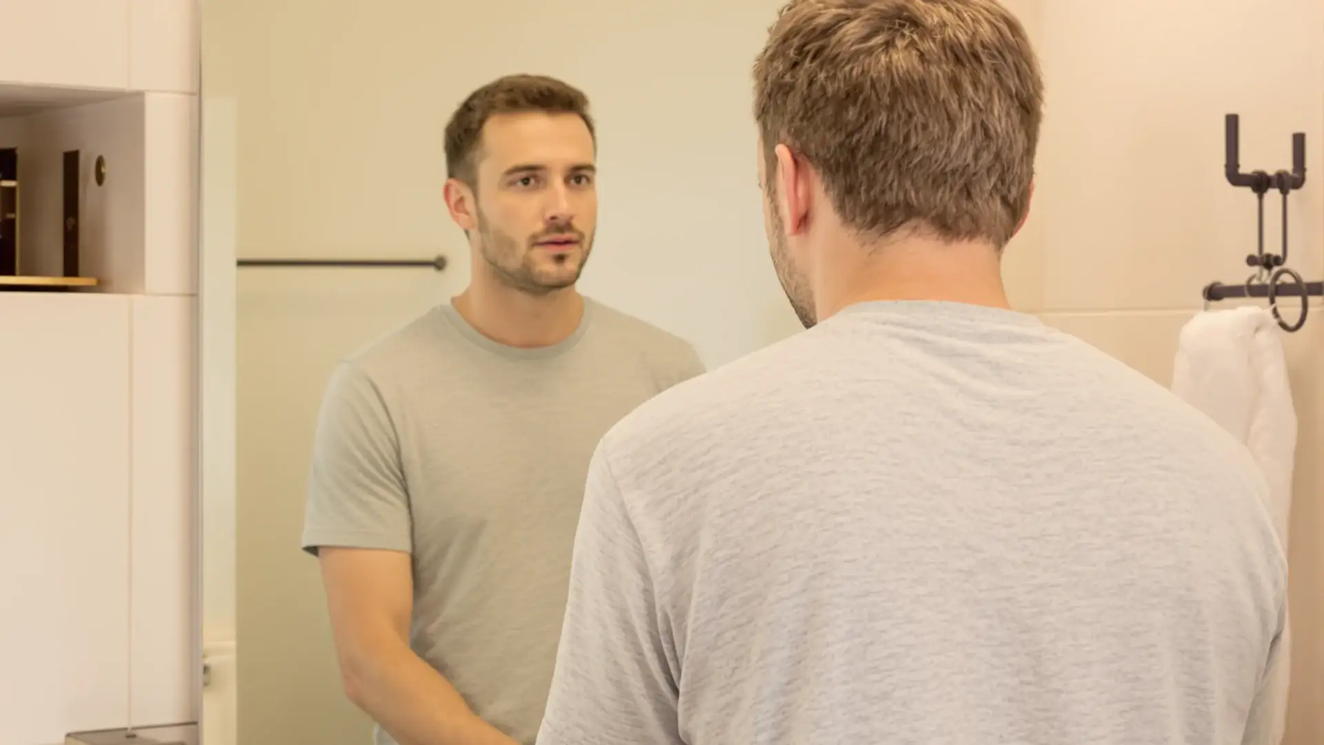 Man checking receding temples in bathroom mirror