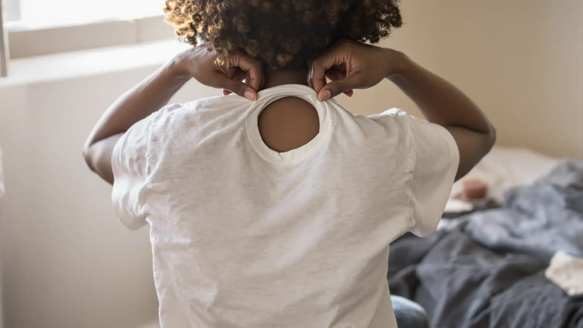 Woman with 4C curls parting her hair to check scalp for thinning